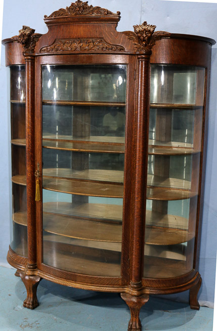 035b - Quarter sawn oak china cabinet with 4 shelves, curved glass front and carved lions heads, 76 in. T, 56 in. W, 19 in. D.