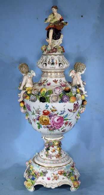 034a - Palace size Dresden capped urn decorated with flowers and large cupids, has painting of royal court and full body figure on top of lid, 36 in. T, 16 in. W.-25