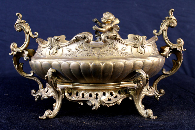 011a - Victorian brass double handle center bowl, very ornate with cherub figures, 12 in. T, 19 in. W, 9 in. D.