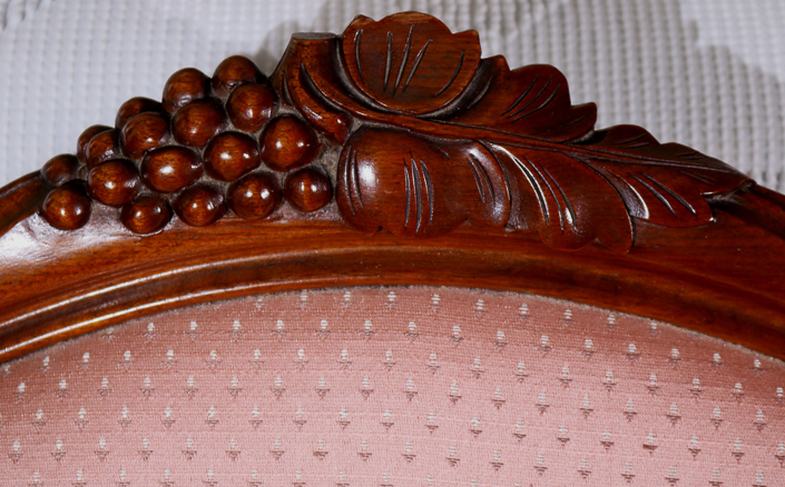 029c - Walnut Victorian loveseat with grape crest and pink upholstery, 31 in. T, 63 in. L, 16 in D.