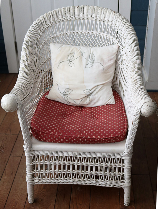 107a - Antique white wicker chair with rolled arms, original to this house, 33 in. T, 26 in. W, 20 in. D.