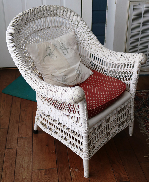 107b - Antique white wicker chair with rolled arms, original to this house, 33 in. T, 26 in. W, 20 in. D.